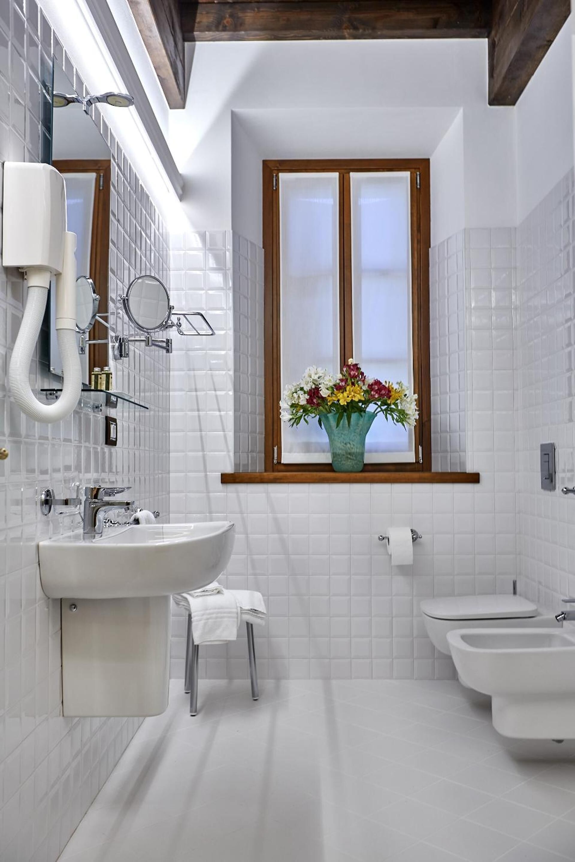A modern bathroom with a large window, a sink, a bidet, and a mirror.