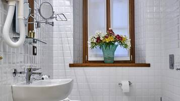 A modern bathroom with a large window, a sink, a bidet, and a mirror.