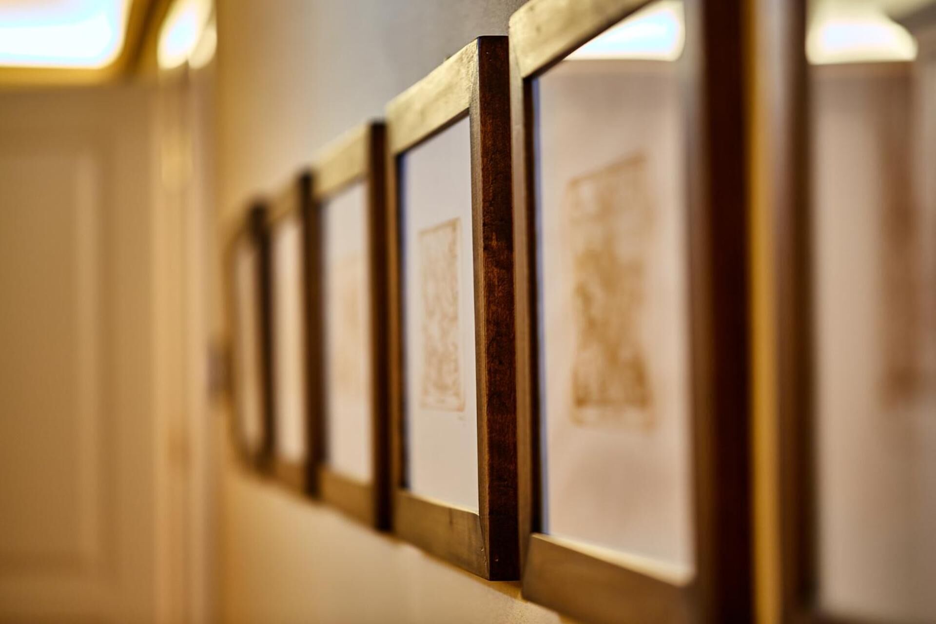 Un pasillo con obras de arte enmarcadas en la pared.