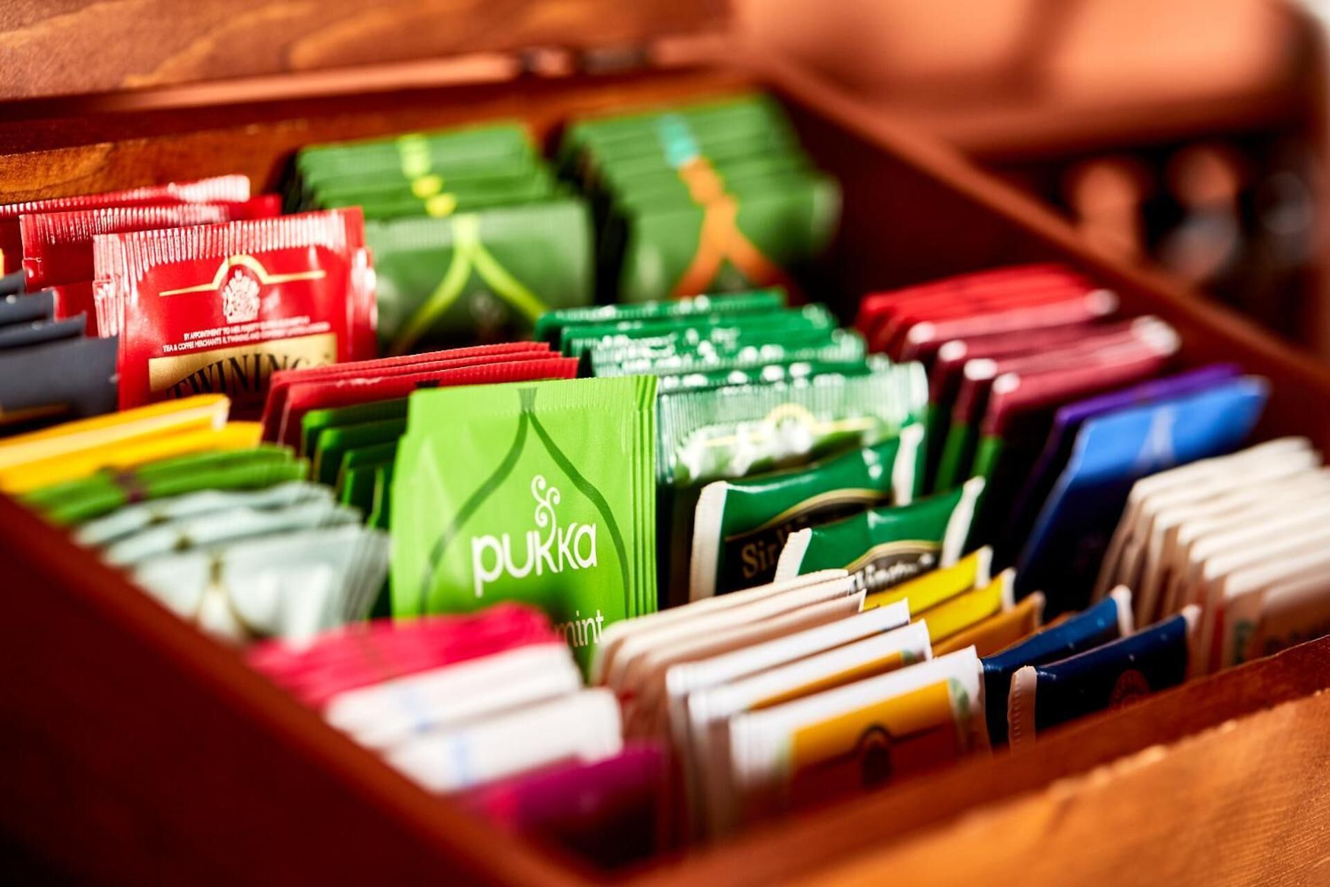 A drawer filled with various colored tea bags, including brands like Pukka and Sir John.