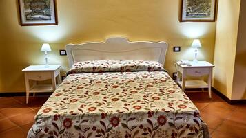A neatly made bed with floral bedding, two bedside tables with lamps, and two framed pictures on the wall.