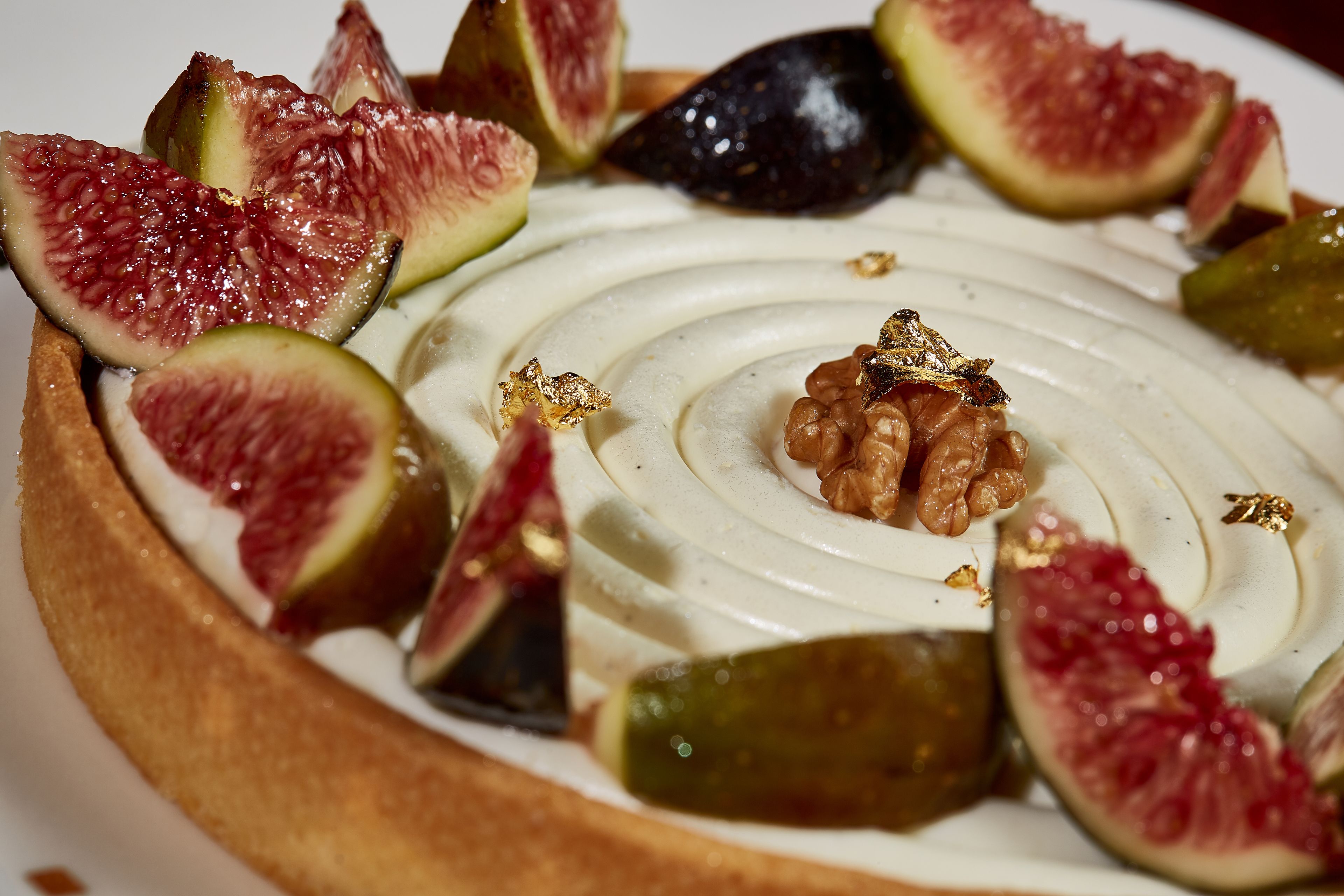 A dessert with a creamy swirl, figs, and walnuts on a plate.