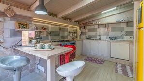 Una cocina compacta con una isla central, estufa a gas y un lavamanos.