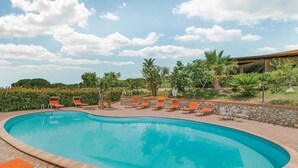 Una piscina con lettini da relax e un muro in pietra.