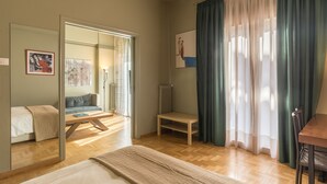 Una habitación con cama, escritorio, silla, mesa y ventana con cortinas.