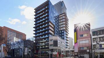 A modern urban hotel with a prominent glass facade, multiple floors, and a central courtyard.