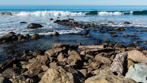 A rocky shoreline with waves crashing against the rocks. - BEAUTIFUL, LUXURY CONDO, GATED WITH WALKING TRAIL TO BEACH! (Dana Point)