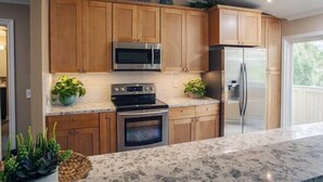 A kitchen with wooden cabinets, stainless steel appliances, and a marble countertop. - BEAUTIFUL, LUXURY CONDO, GATED WITH WALKING TRAIL TO BEACH! (Dana Point)