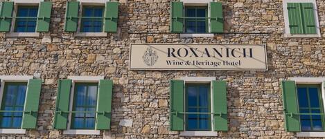 Un edificio de piedra con un cartel que dice "ROXANICH Wine & Heritage Hotel".
