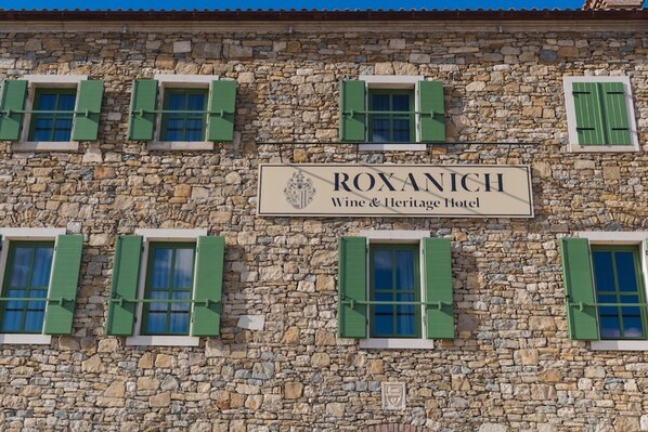 A stone building with a sign that reads "ROXANICH Wine & Heritage Hotel".