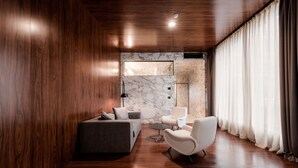 A modern room with wooden walls, a marble accent wall, a sofa, two white armchairs, and a small table. - ROXANICH Winery and Design Hotel (Motovun)