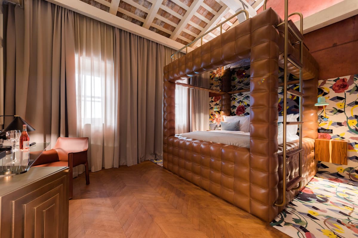 A bedroom with a large, cushioned bed, a wooden desk, and a chair.