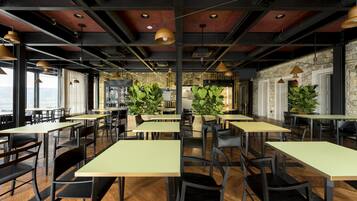 Un restaurante moderno con techos altos, vigas a la vista y amplias ventanas que ofrecen vistas. Las mesas están dispuestas en un espacio amplio con sillas.