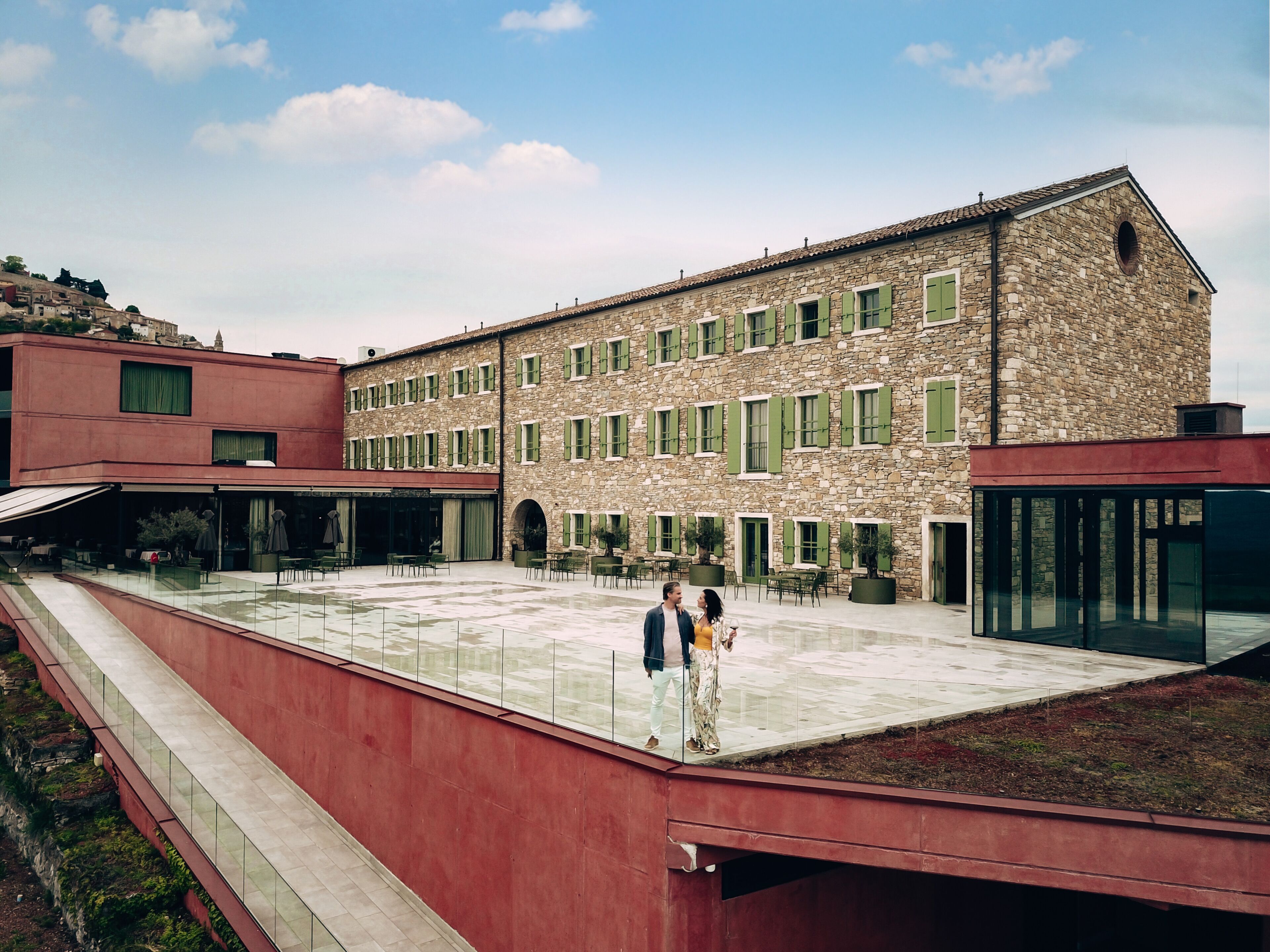 A courtyard with a stone building, outdoor seating, and a glass railing.