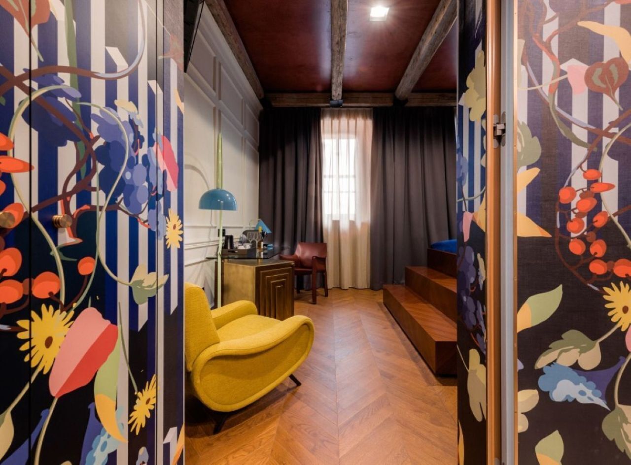 Une pièce avec un plancher en bois, une chaise jaune, un bureau avec une lampe et une vue sur un escalier.