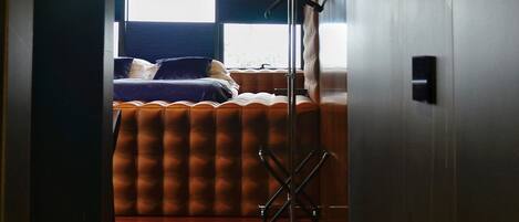 Una habitación con cama, una lámpara de pie y un ventanal con persianas.