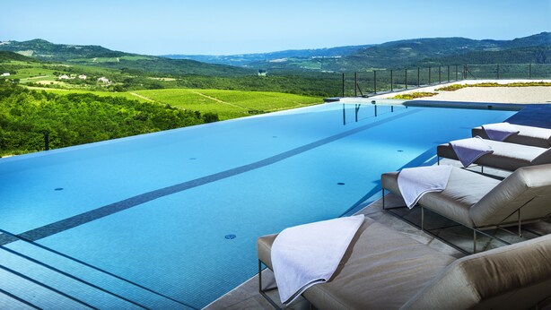 A pool area with lounge chairs and a view of green hills. - ROXANICH Winery and Design Hotel (Motovun)