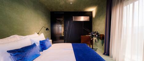 A modern hotel room with a large bed, a desk, and a bathroom visible through an open door.