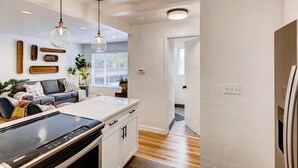 A modern kitchen with a built-in stove, white cabinets, and pendant lighting.