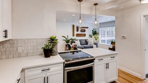 A modern kitchen with white cabinets, a black stove, and pendant lighting.