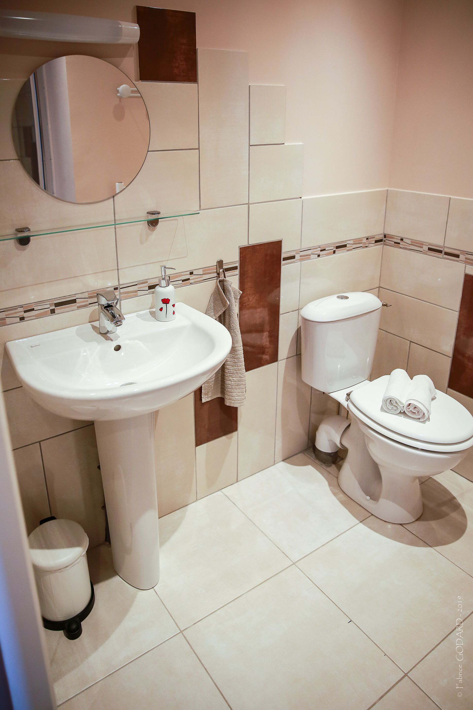 Een badkamer met een witte wastafel, toilet en spiegel.
