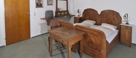 A bedroom with a wooden bed, a wooden nightstand, a wooden dresser, and a wooden desk.