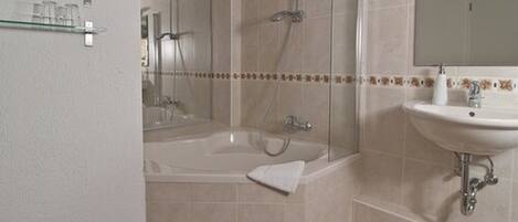A bathroom with a bathtub, shower, and sink.