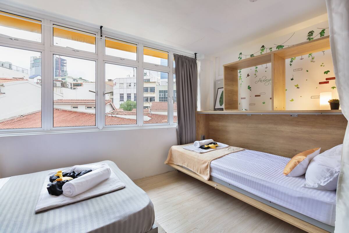 Une chambre d’hôtel avec un lit, une petite table et une fenêtre avec des rideaux.