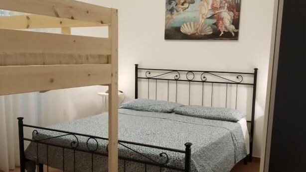 A room with a bunk bed, a single bed, a wooden desk, and a painting on the wall. - Il Giardino fra gli Ulivi (Torino di Sangro)