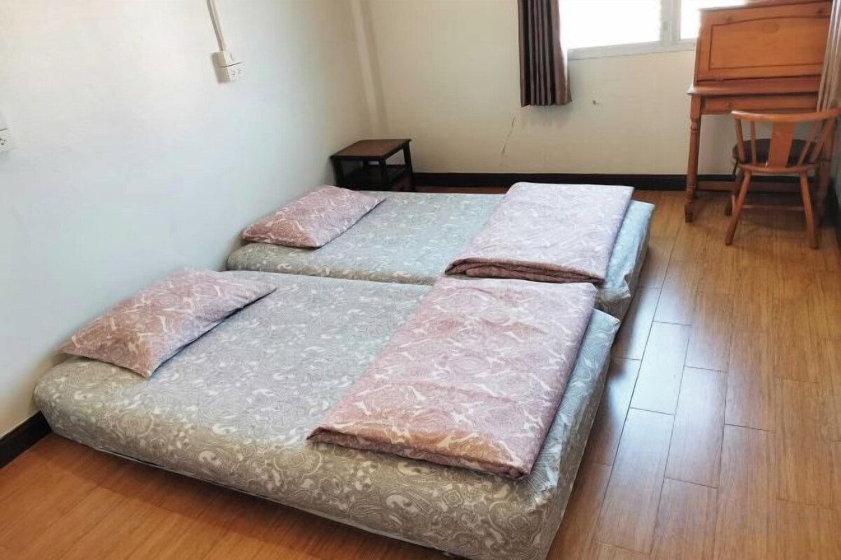 A room with two beds, a small table, and a chair.