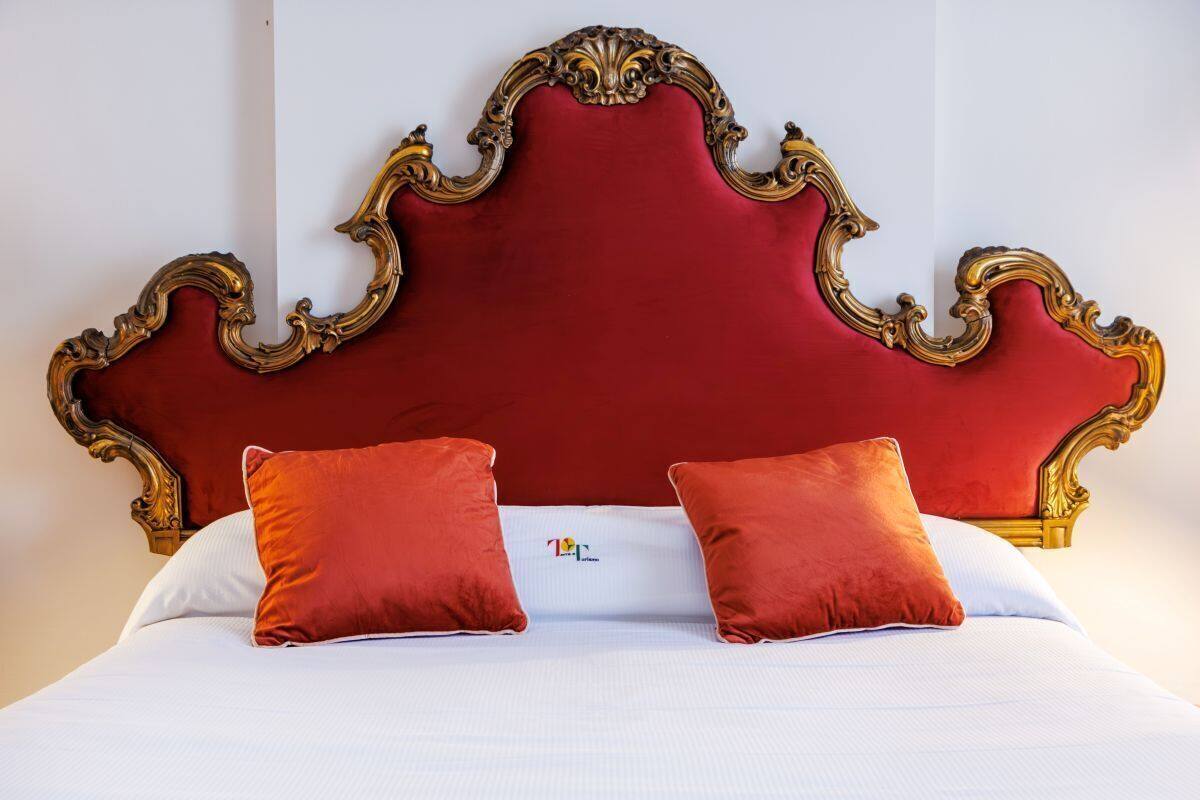 A bed with a red upholstered headboard, two red pillows, and white bedding.