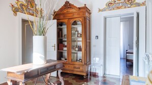 Quarto com um armário de madeira, um vaso branco com plantas e um chão com azulejos hexagonais.