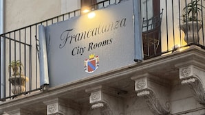Fachada de edifício com uma placa que diz "Franca deza City Rooms" e um brasão.