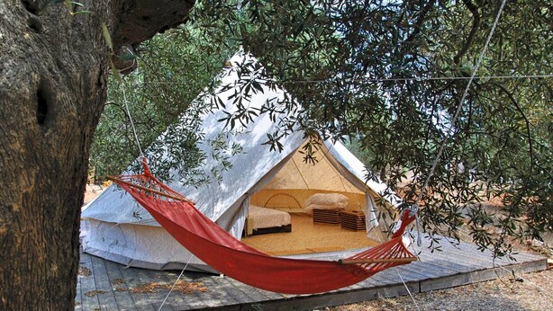 A treehouse-style tent with a hammock, surrounded by foliage. - Accampamento Rurale Macaria (Alliste)