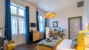 A well-lit room with a bed, a desk, a chair, and a television. - Chambres d'hôtes H De Surgeres (Surgeres)
