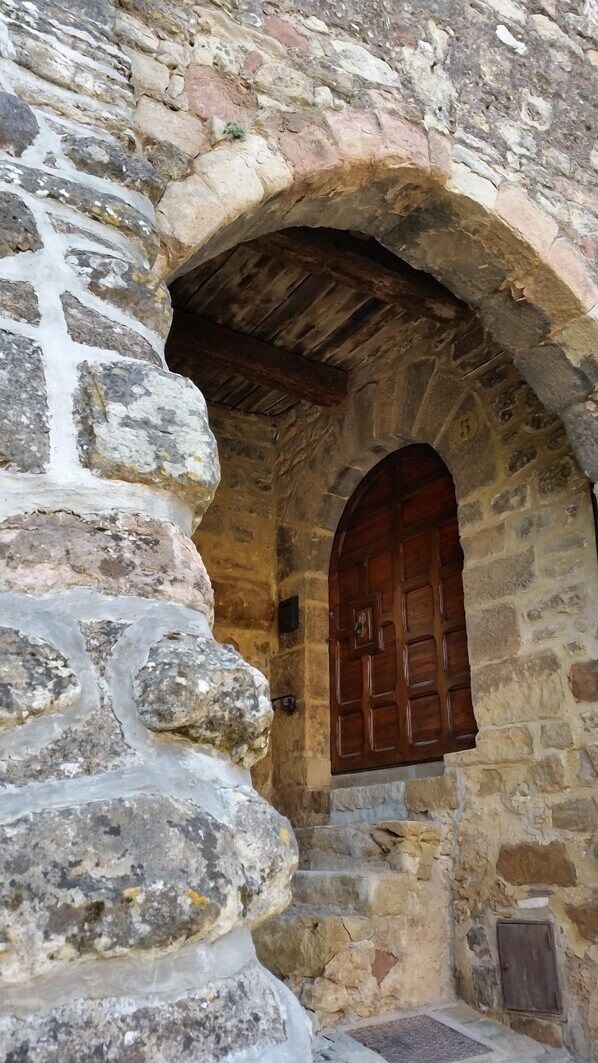 A stone building with an arched doorway and a wooden door.
