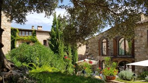 Un patio con edificios de piedra, abundante vegetación y zonas de estar al aire libre.