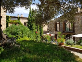 Un patio con edificios de piedra, abundante vegetación y zonas de estar al aire libre.