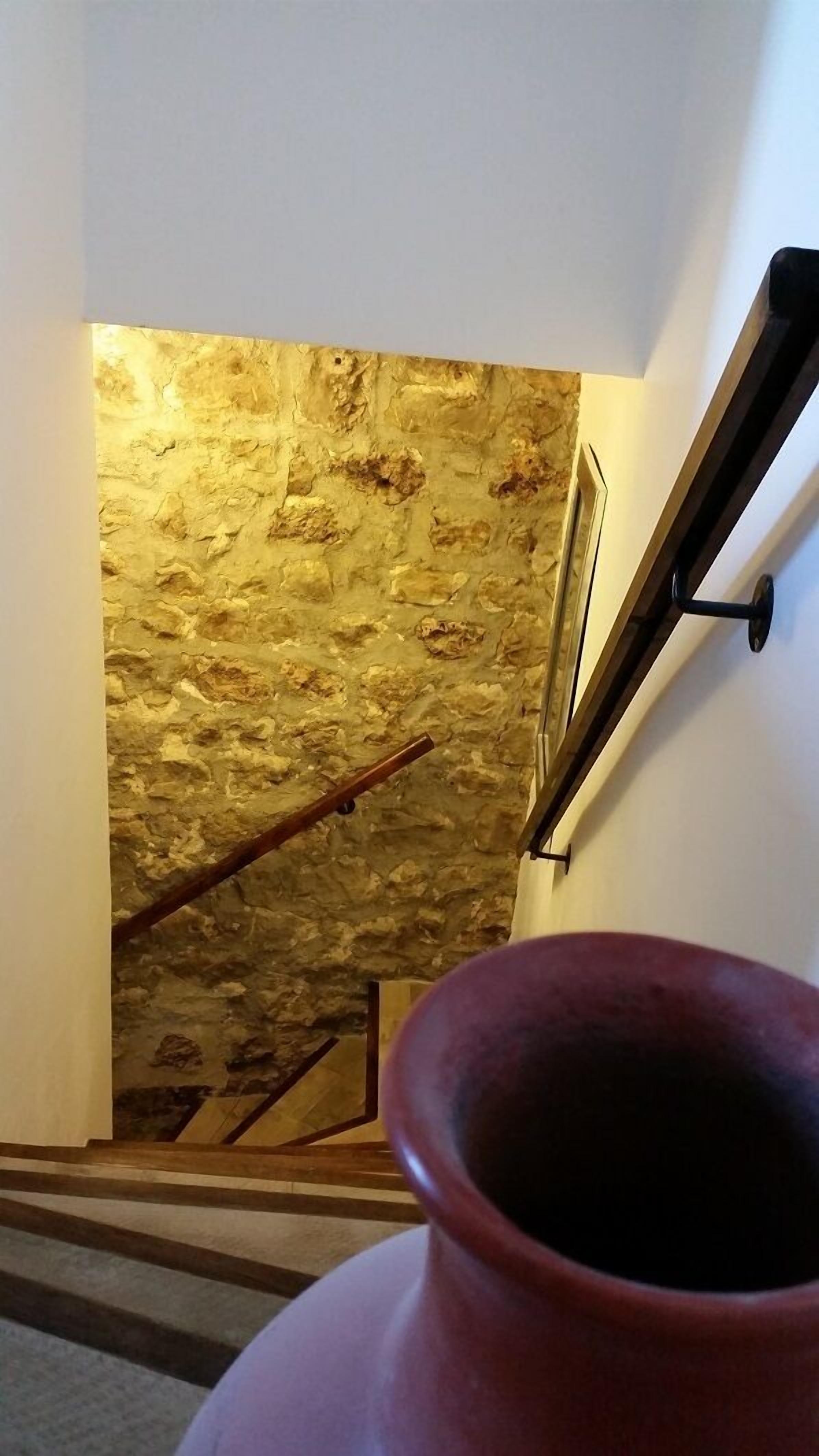Una scala con una parete in pietra strutturata e una ringhiera in legno.