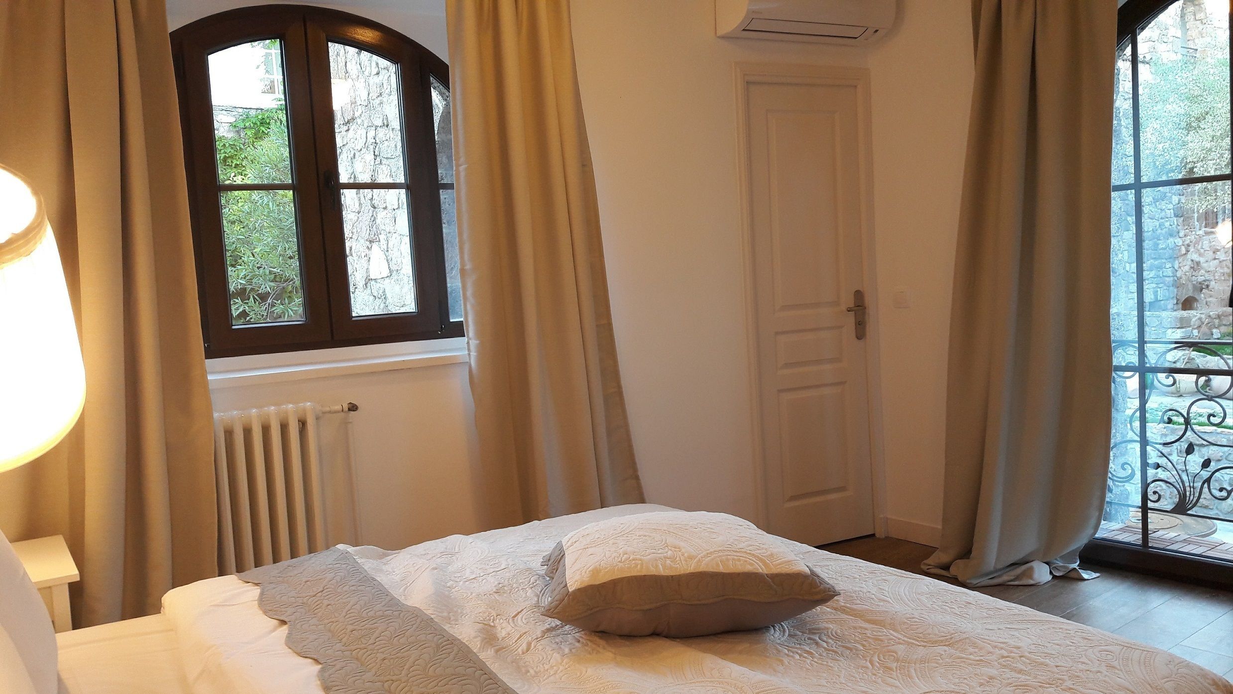 A bedroom with a bed, a radiator, a window, and curtains.