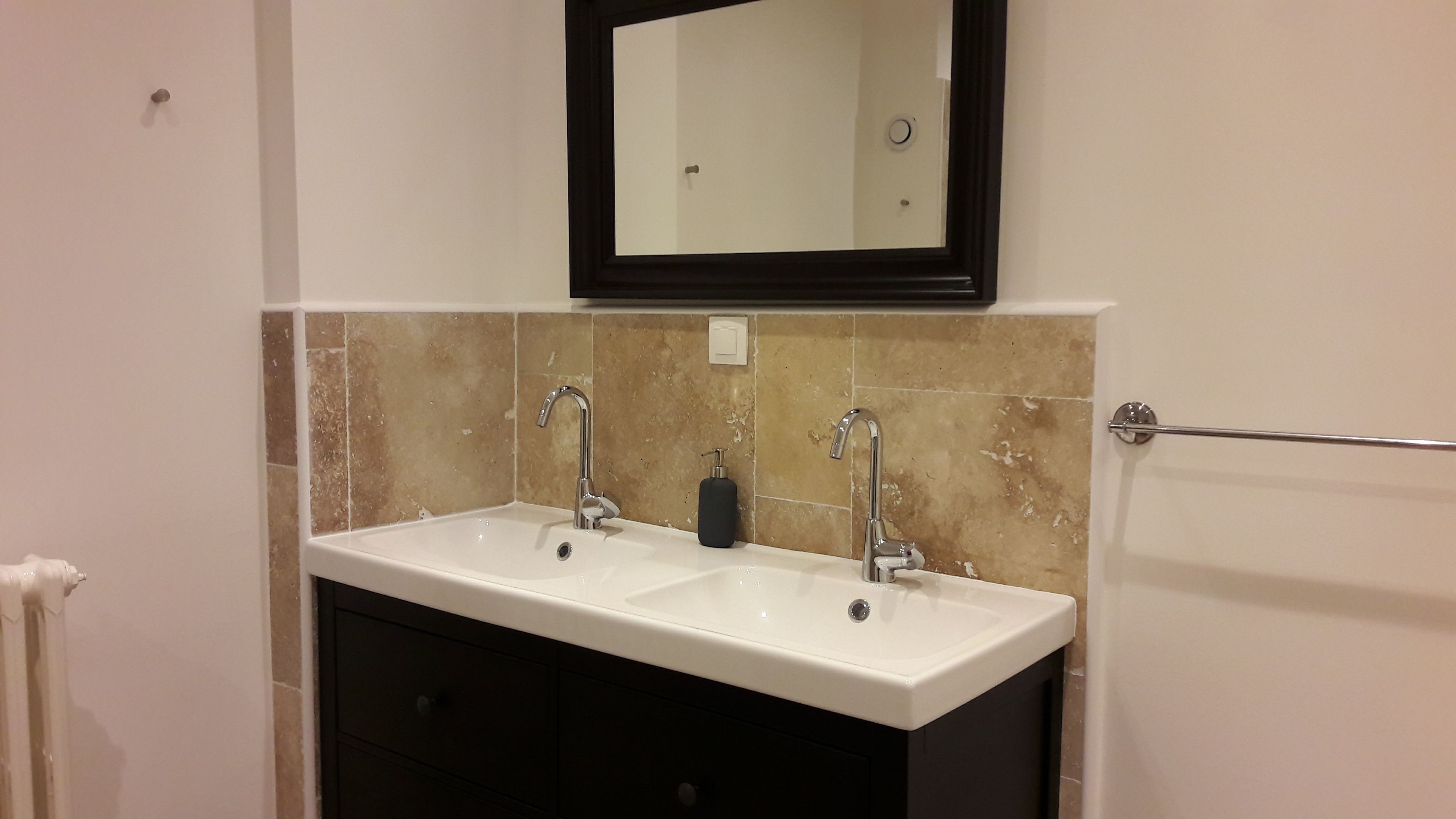Une salle de bain avec deux lavabos, un miroir et un porte-serviettes.