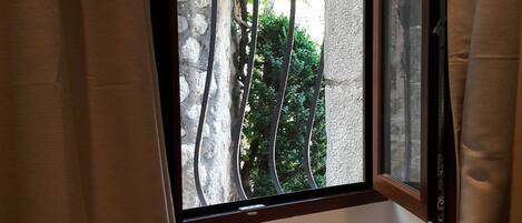 A room with a window featuring metal bars, a small wooden table, and a chair.