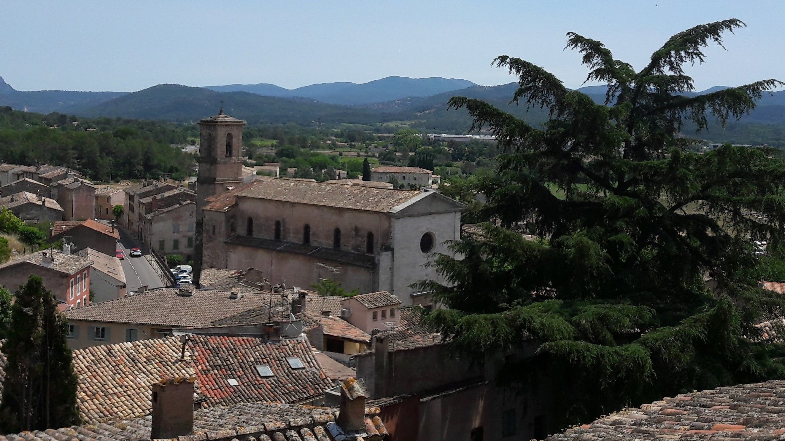 A historic town with a prominent church featuring a bell tower, surrounded by traditional buildings and lush greenery.