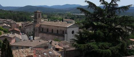 Un pueblo histórico con una iglesia destacada que presenta un campanario, rodeado de edificios tradicionales y exuberante vegetación.
