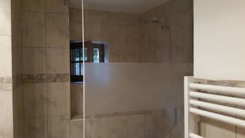 A bathroom with tiled walls, a shower area, and a window.