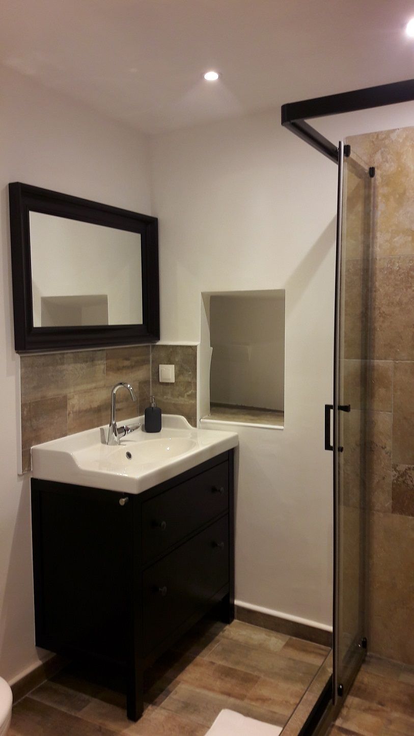 A modern bathroom with a large mirror, a sink, and a glass shower enclosure.