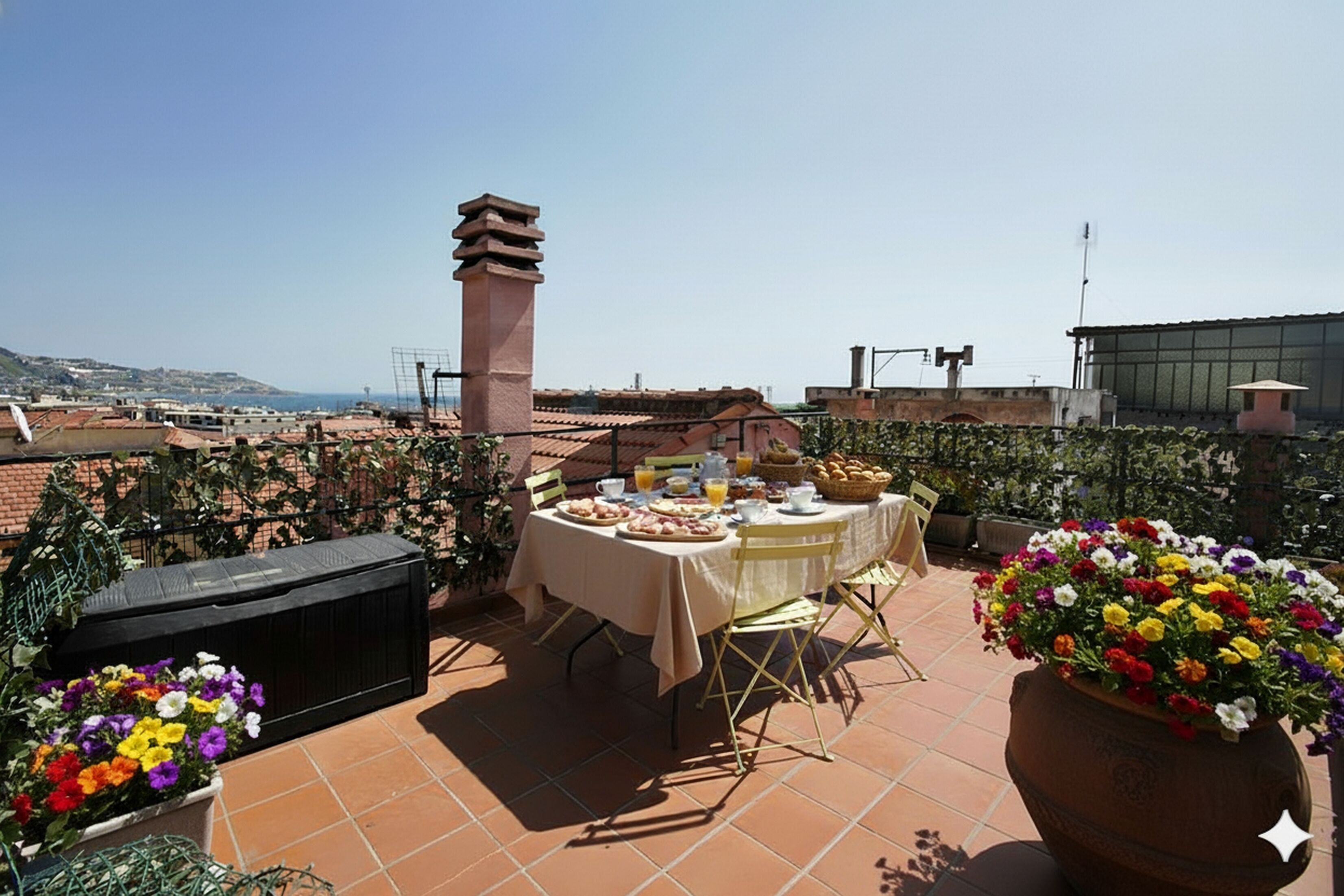 Una terrazza sul tetto con un tavolo apparecchiato per la colazione, circondata da piante in vaso e vista sulla città.