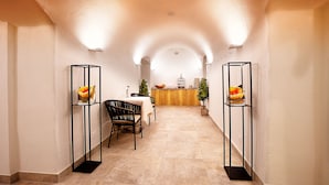 Un pasillo con zona de comedor, que incluye una mesa y sillas de madera, un mostrador de recepción y dos vitrinas de cristal con flores.