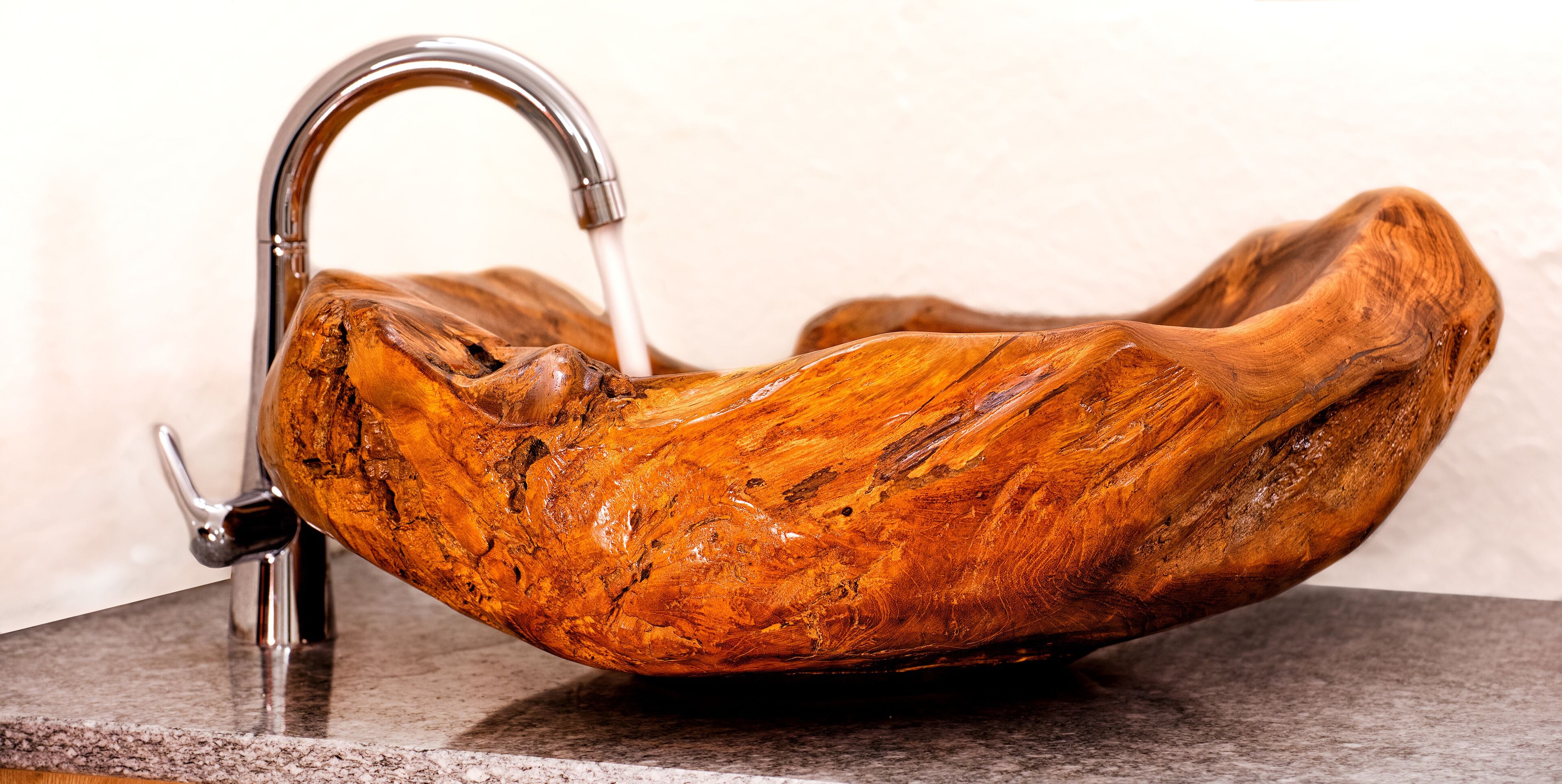 Een wasbak van hout met een moderne kraan.