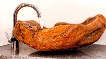 Een wasbak van hout met een moderne kraan.